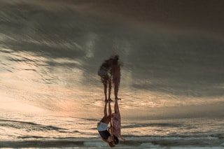Couple reflected on wet sand at sunset