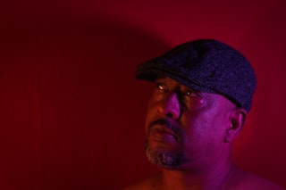 Man wearing a flat cap with dramatic lighting.