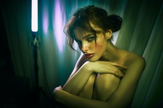 a naked woman is posing in front of a curtain
