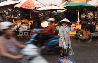 Woman in conical hat at a busy market street
